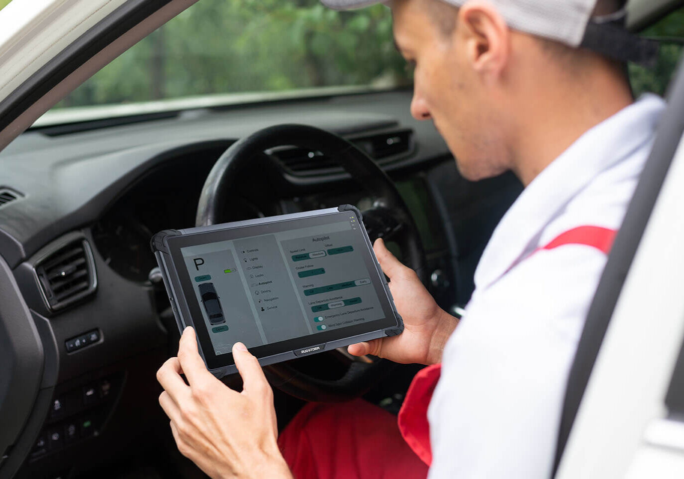 a white T shirt man holding a rugged tablet in a car